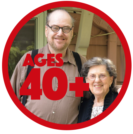 Adult son with developmental disabilities and his senior mother standing on their back porch, smiling.
