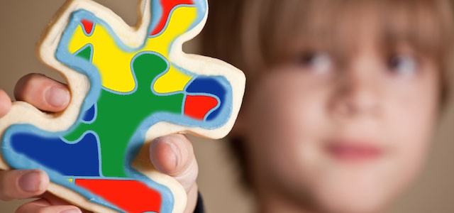 boy holding multi-colored puzzle piece in his hand