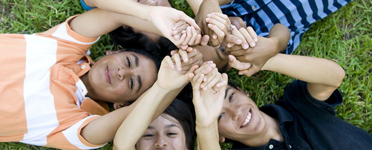 teens on grass, looking up, holding hands