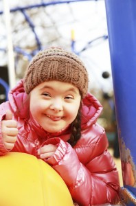 Girl with Down syndrome on swings, smiling
