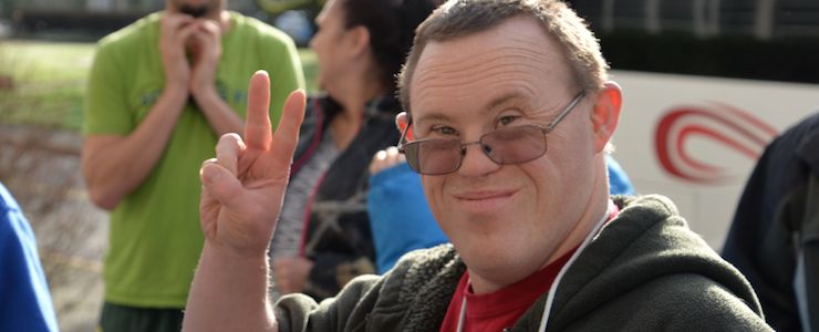Man with Down syndrome making a peace sign.