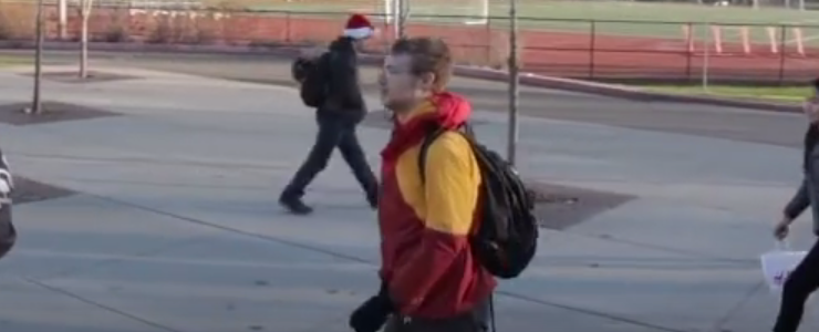 male studen with backpack walks across high school campus