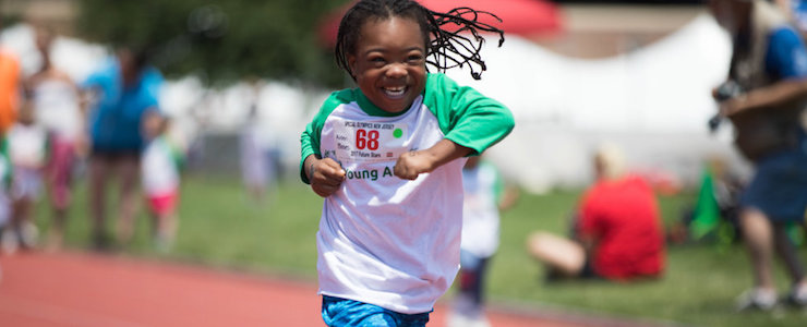Smiling young African American athlete running on a track.