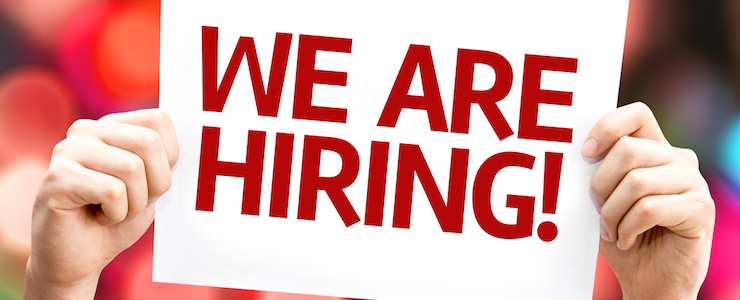 Hands holding up a We are Hiring card with colorful background.
