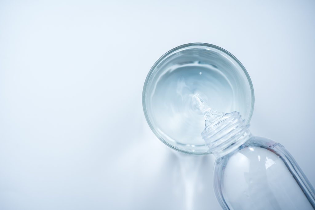 pouring water from bottle into glass on white background