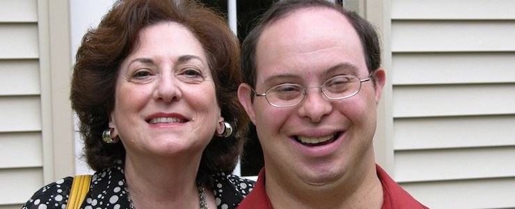Close up of mother and adult son with Down syndrome, smiling.