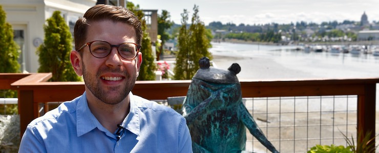 Jeremy Norden-Paul, smiling, outside, Budd Bay and Capitol Building in the background.