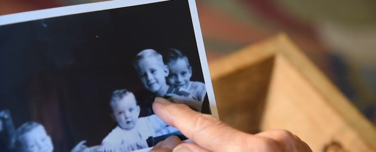 A hand pointing to an old black and white photo of siblings.