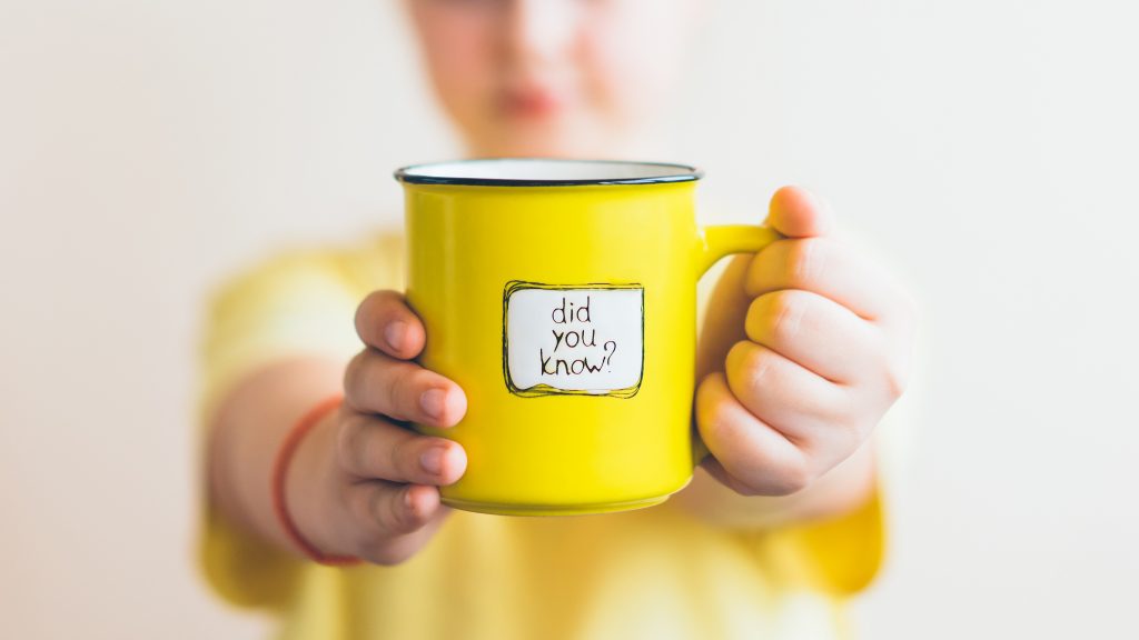 A girl in a yellow T-shirt with a yellow cup in her hand, on which was written Did you know. Interesting fact.