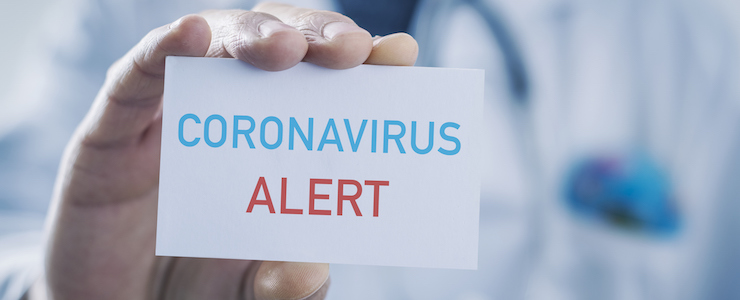 Closeup of a caucasian doctor man showing a sign with the text coronavirus alert written in it.