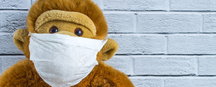 Toy plush monkey in a homemade medical mask on the background of a brick wall with space for copying. Concept - protection from coronavirus.