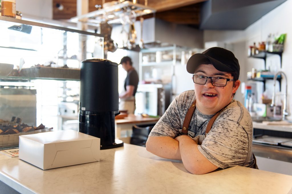A man with Down syndrome working at the counter of a coffee shop.