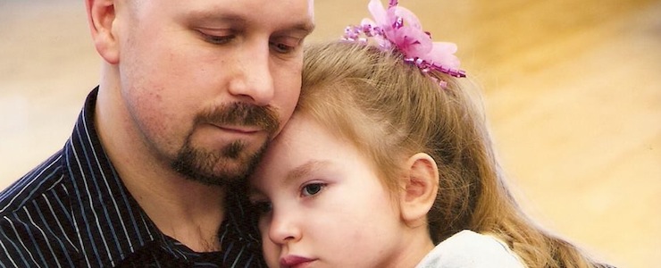 Father holding young daughter close to him..